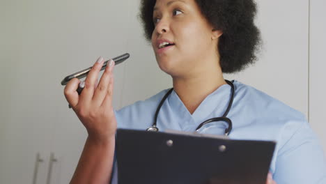 Video-of-focused-plus-size-african-american-female-doctor-using-smartphone