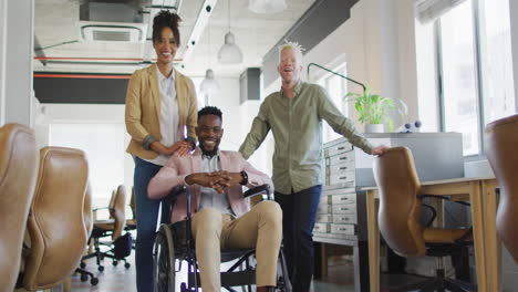 Portrait-of-happy-diverse-business-people-with-disabled-colleague-in-creative-office