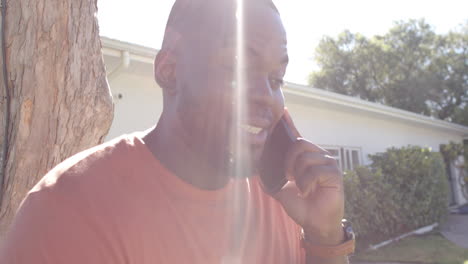 Happy-african-american-man-talking-on-smartphone-in-sunny-garden,-in-slow-motion