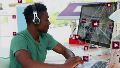 Animation-of-connected-dots-forming-globes-over-african-american-man-listening-to-music-and-working