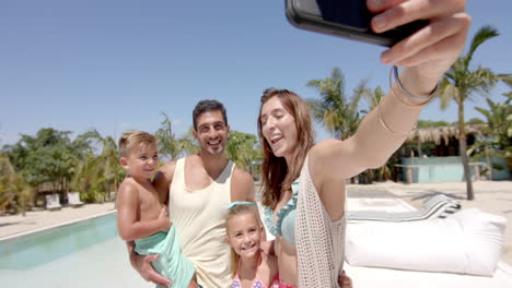 Happy-caucasian-family-taking-selfie-with-smartphone-at-beach-house