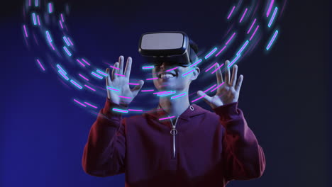 Animation-of-glowing-light-trails-of-data-transfer-and-asian-man-in-vr-headset