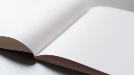 Close-up-of-open-blank-book-with-copy-space-on-gray-background-in-slow-motion