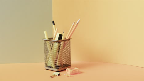 Close-up-of-school-stationery-in-cup-with-copy-space-on-yellow-background,-in-slow-motion