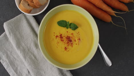 Video-of-cream-vegetable-soup-in-bowl-on-grey-table-with-carrots