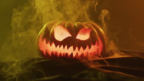 Video-of-halloween-carved-pumpkin-with-smoke-and-orange-light-on-black-background