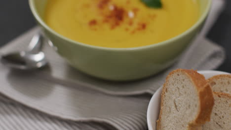 Video-of-cream-vegetable-soup-in-bowl-on-grey-table-with-bread
