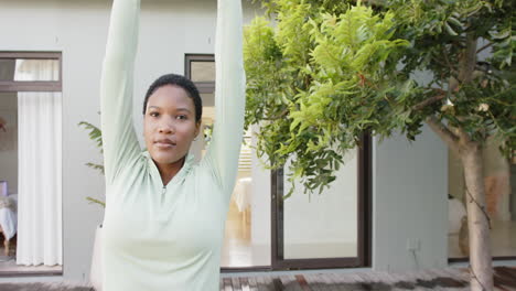 Retrato-De-Una-Mujer-Birracial-Enfocada-Practicando-Yoga-Y-Estirándose-En-El-Jardín,-Cámara-Lenta