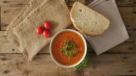 Video-of-cream-tomato-soup-in-bowl-on-wooden-table-with-bread