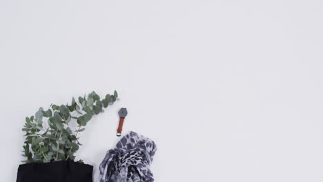 Video-Einer-Schwarzen-Canvas-Tasche-Mit-Pflanze,-Schal,-Uhr,-Kopierraum-Auf-Weißem-Hintergrund