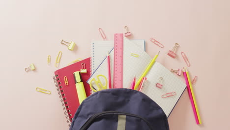 Video-of-backpack-with-school-items-on-pale-pink-surface