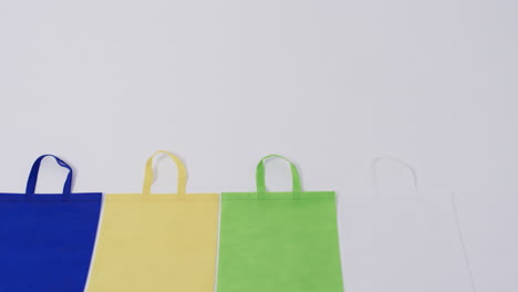 Video-of-row-of-multi-coloured-canvas-bags-with-copy-space-on-white-background