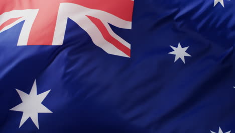 White-rugby-ball-rolling-over-waving-flag-of-australia-with-copy-space,-in-slow-motion