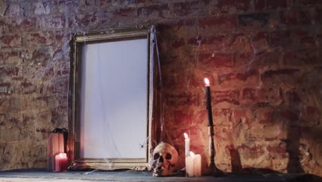 Video-of-stack-of-books,-frame-with-spider-web,-skull-and-candles-on-brick-wall-background