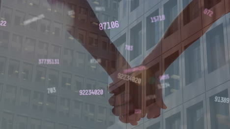 Animation-of-changing-numbers-over-building-and-diverse-couple-holding-hands-against-sky