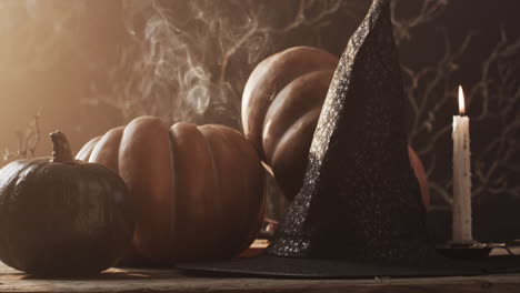 Video-of-halloween-pumpkins,-hat,-candle-and-copy-space-on-brown-background