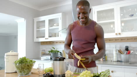 Feliz-Hombre-Afroamericano-Preparando-Batido-Saludable-En-La-Cocina-De-Casa,-Cámara-Lenta
