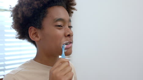 African-american-boy-brushing-teeth-in-bathroom,-slow-motion