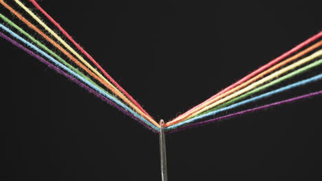 Video-Von-Mikro-Von-Regenbogenfarbenen-Fäden,-Die-Durch-Die-Nadel-Laufen,-Mit-Kopierraum-Auf-Schwarzem-Hintergrund