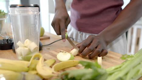 Midsection-of-african-american-man-preparing-healthy-smoothie-in-kitchen-at-home,-slow-motion