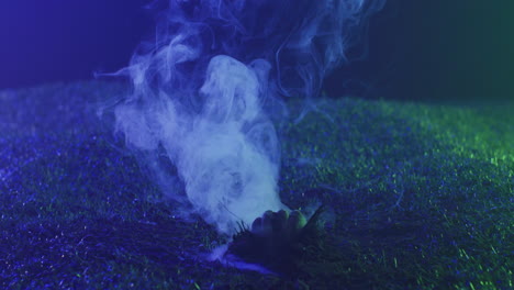 Video-of-hand-raising-from-grass-with-smoke-on-black-background