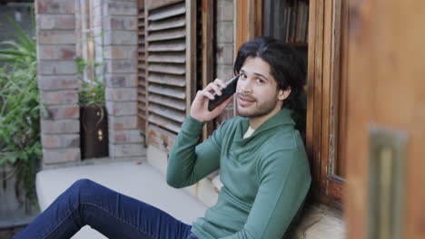 Happy-caucasian-man-talking-on-smartphone-sitting-by-window,-slow-motion
