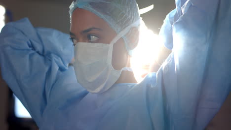Biracial-Weibliche-Chirurgin-Mit-Gesichtsmaske-Im-Operationssaal,-Zeitlupe