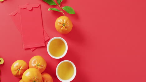 Video-of-envelopes,-oranges-and-bowls-on-red-background