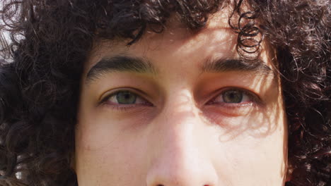 Close-up-video-portrait-of-eyes-of-biracial-man-smiling-to-camera-outdoors