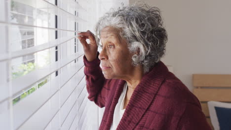 Nachdenkliche-ältere-Afroamerikanische-Frau,-Die-Durch-Das-Fenster-Schaut
