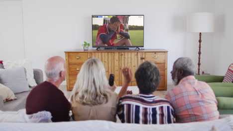 Video-Einer-Gruppe-älterer-Menschen,-Die-Auf-Der-Couch-Sitzen-Und-Sich-Ein-Fußballspiel-Ansehen