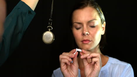 Woman-breaking-a-cigarette-in-front-of-a-pendulum-to-stop-smoke-