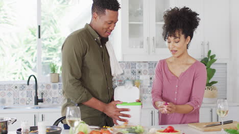 Happy-african-american-couple-cooking-and-dumping-waste-in-kitchen