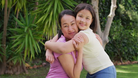 Video-Einer-Glücklichen-Asiatischen-Mutter-Und-Tochter,-Die-Sich-Im-Garten-Umarmen