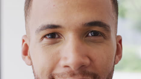 Close-up-video-portrait-of-of-biracial-man-smiling-to-camera-indoors