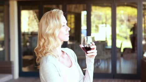 Smiling-blonde-woman-standing-and-holding-wineglass