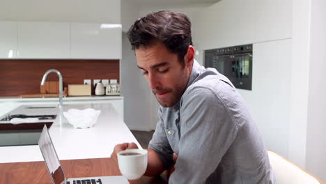 Hombre-Guapo-Tomando-Café-Y-Usando-Una-Computadora-Portátil