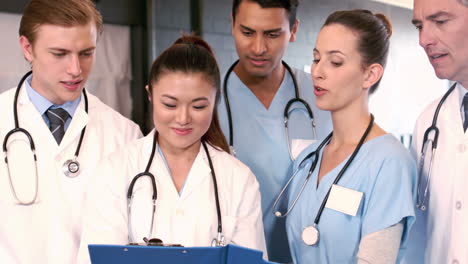 Medical-team-talking-together-while-looking-clipboard