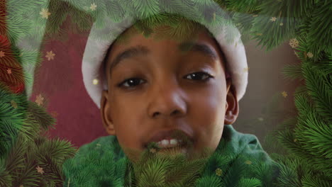 Animation-of-fir-tree-and-snowflakes-over-african-american-boy-wearing-santa-hat