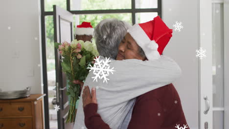 Animation-of-white-christmas-snowflakes-over-diverse-senior-female-friends-hugging-in-doorway