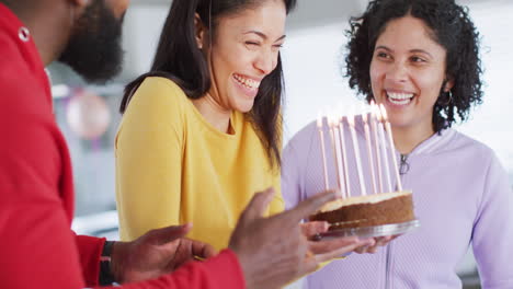 Laughing-biracial-woman-holding-birthday-cake-celebrating-with-diverse-friends,-in-slow-motion