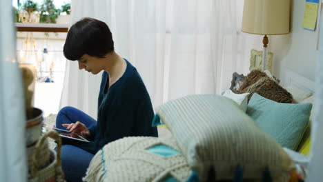 Woman-using-digital-tablet-in-bedroom