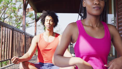 Glückliches-Afroamerikanisches-Paar,-Das-Yoga-Macht-Und-In-Der-Blockhütte-Meditiert,-Zeitlupe