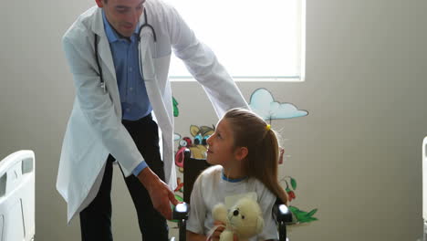 Male-doctor-interacting-with-child-patient-in-ward