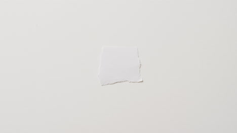Video-of-close-up-of-torn-piece-of-paper-with-copy-space-on-white-background