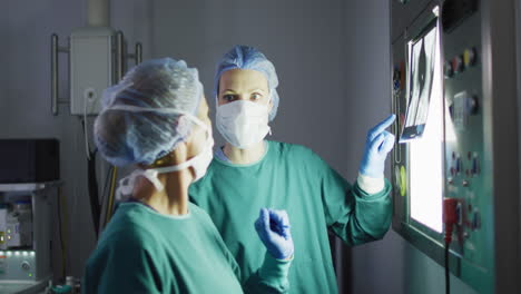 Video-Von-Zwei-Verschiedenen-Weiblichen-Chirurgen,-Die-über-Röntgenaufnahmen-Im-Operationssaal-Diskutieren