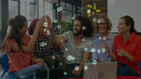Animation-of-globe-of-digital-icon-over-group-of-diverse-colleagues-high-fiving-each-other-at-office
