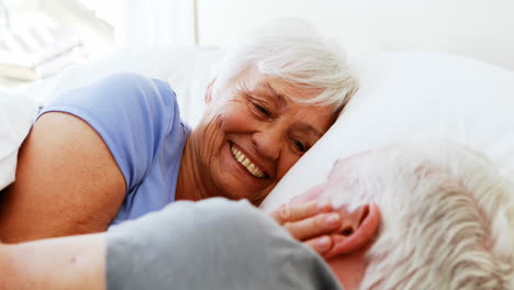 Happy-senior-couple-interacting-with-each-other-while-lying-on-bed-