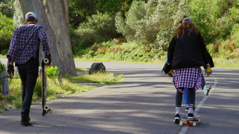 Rear-view-of-cool-young-caucasian-male-skateboarders-walking-with-skateboard-at-countryside-road-4-4
