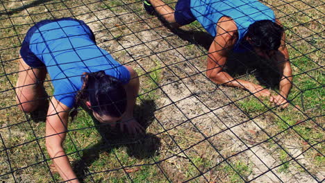 Couple-crawling-under-the-net-during-obstacle-course